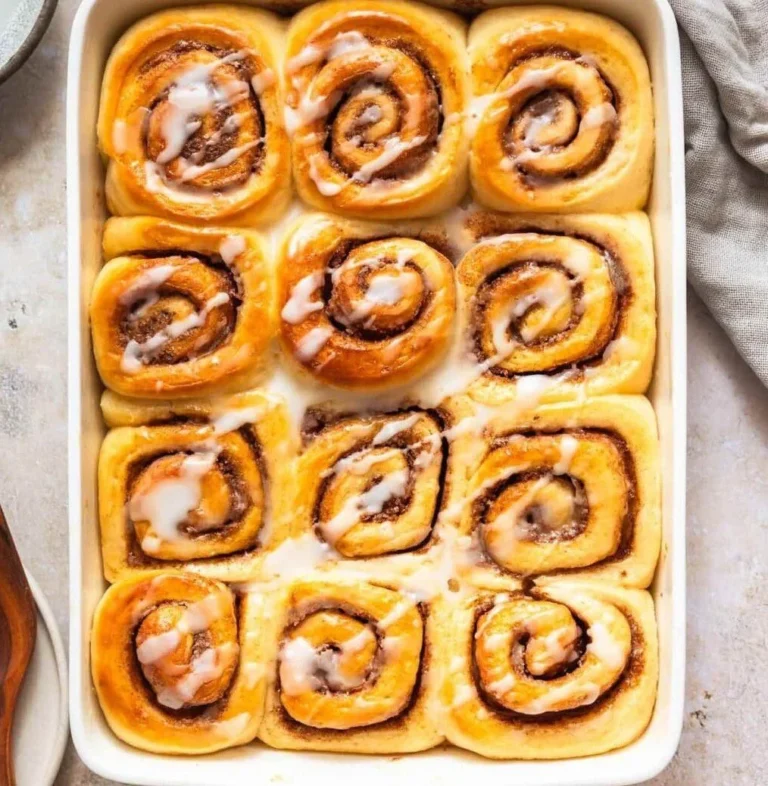 Delicious vegan cinnamon rolls topped with creamy glaze on a wooden table