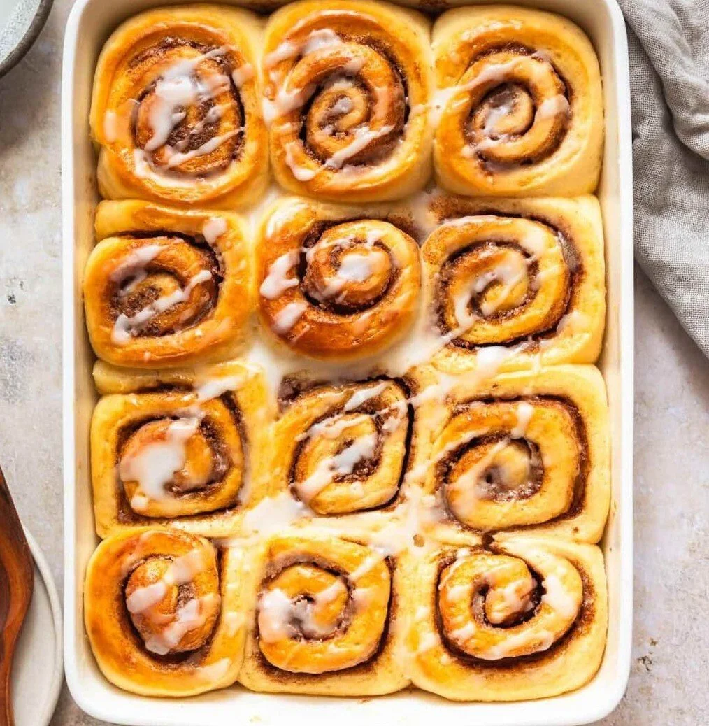 Delicious vegan cinnamon rolls topped with creamy glaze on a wooden table