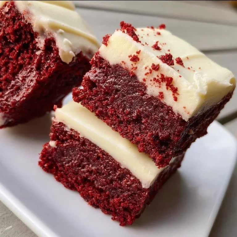 Chewy red velvet brownies with cream cheese frosting on a white plate