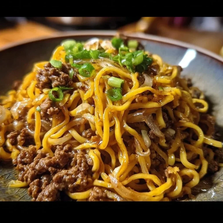 A plate of Mongolian ground beef noodles garnished with green onions.