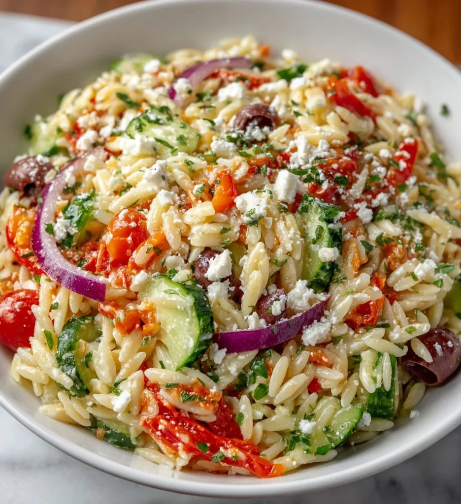 Delicious orzo salad with fresh vegetables and herbs in a bowl.
